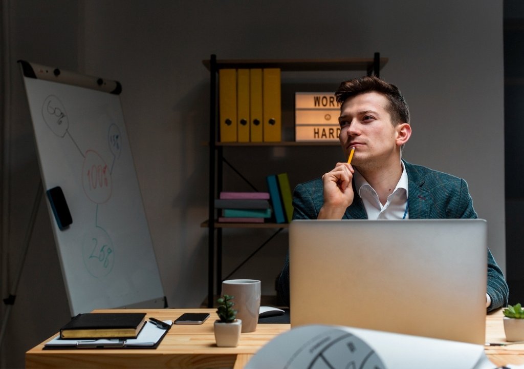 Professional consultant analyzing business strategy and startup plans on a laptop with a whiteboard background.